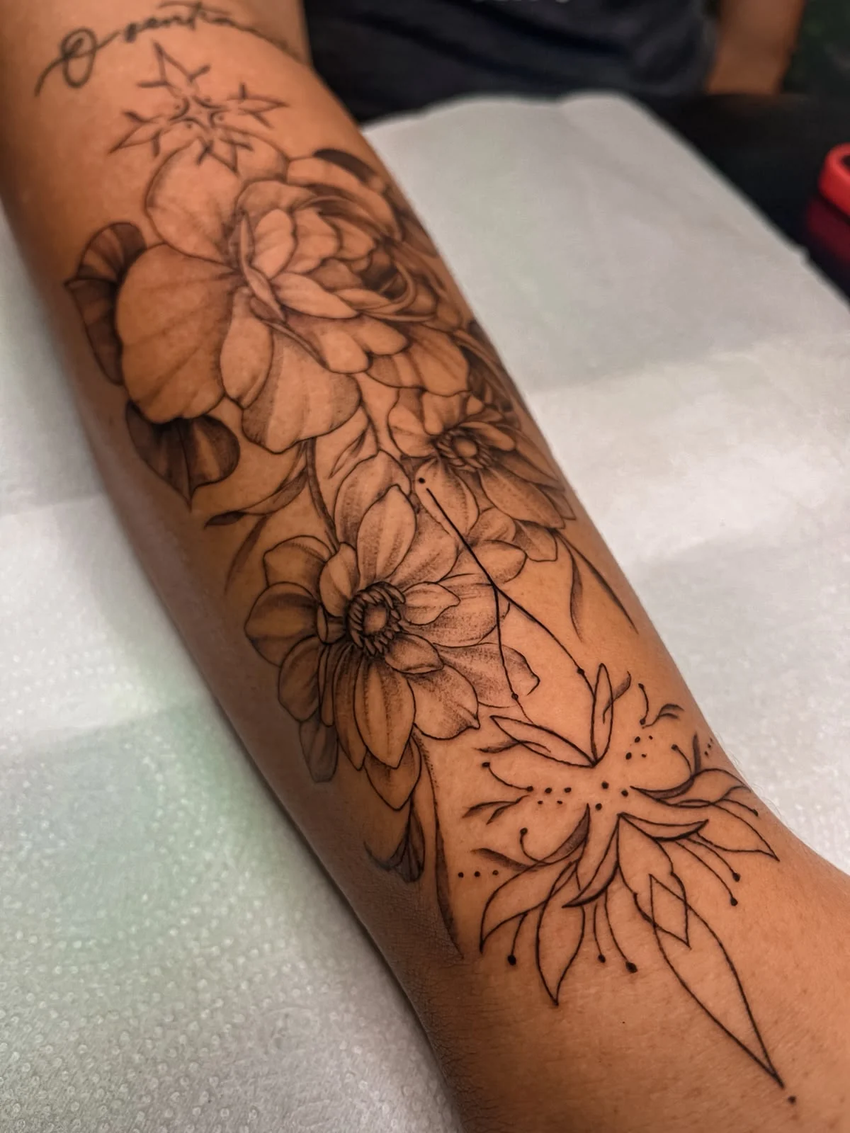 Projeto floral em fine line no antebraço, criado por Thay